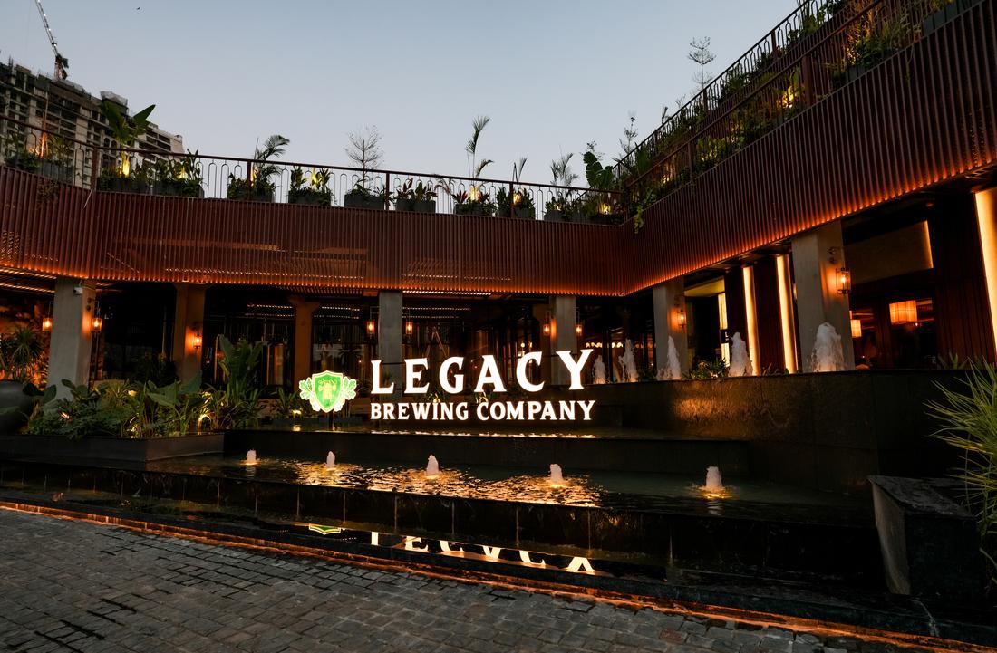 The illuminated entrance and signage of Legacy Brewing Company in RR Nagar